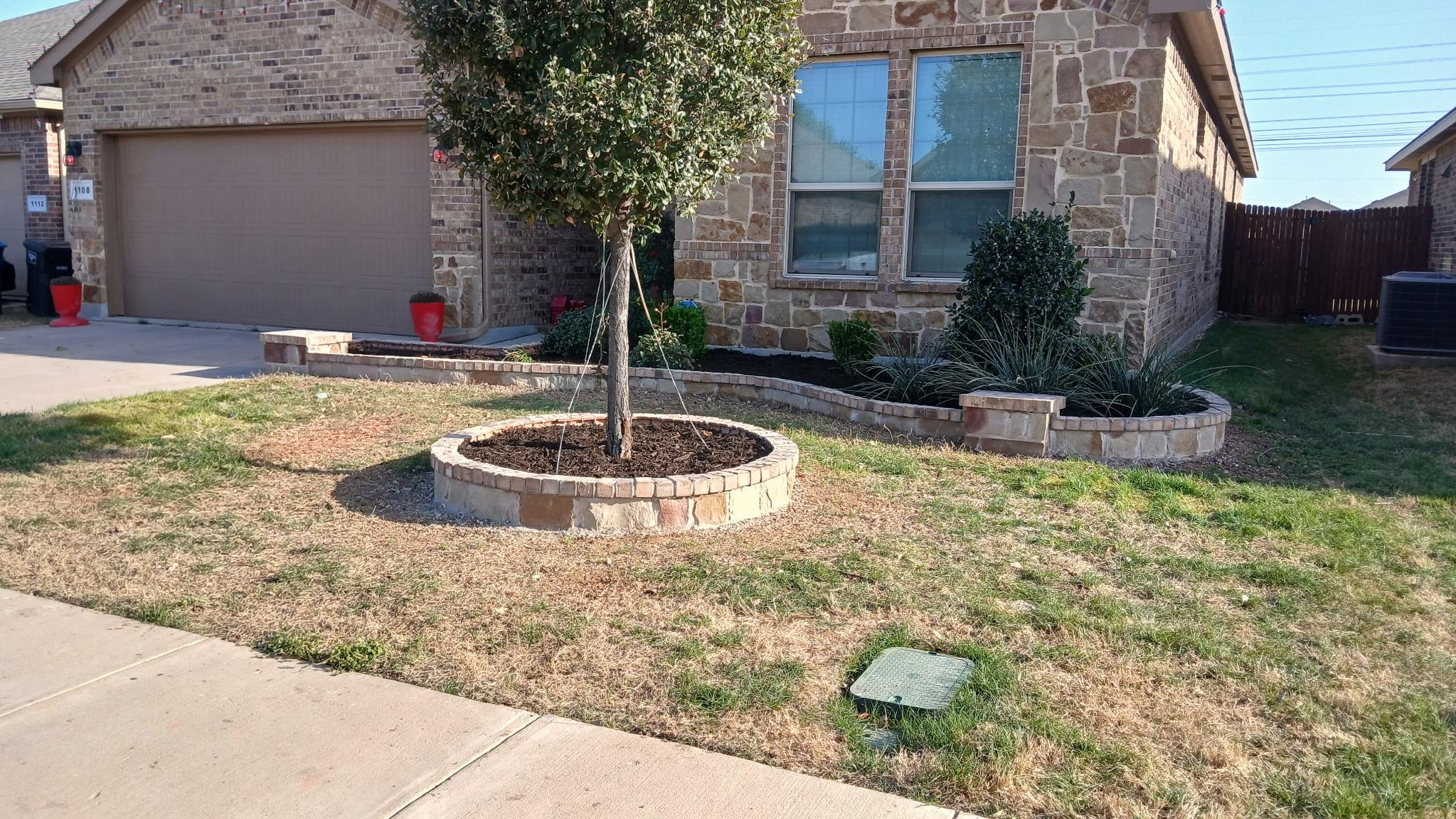 Residential hardscaping: stone retaining borders and mulched beds in a front yard