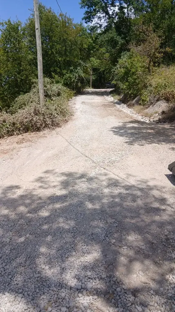 Compacted gravel access path with a crushed-stone shoulder after track-loader grading