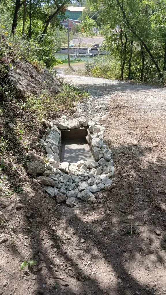 Catch basin and riprap inlet at the bottom of a graded lakeside driveway
