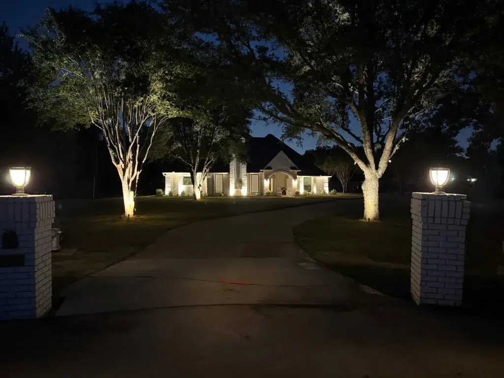 Southlake outdoor lighting: driveway lanterns, tree uplights, and a wall-washed white brick home