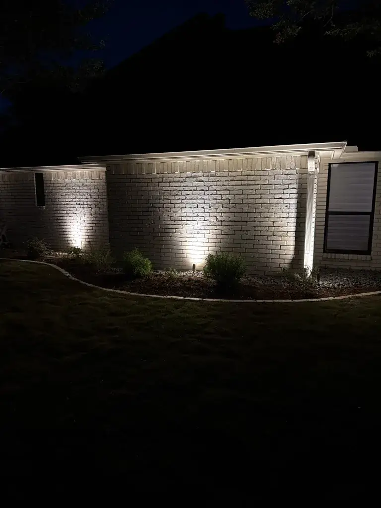 Southlake foundation uplights washing light brick and a black-framed window