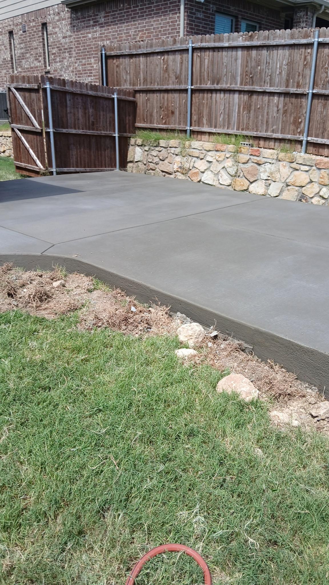 Finished concrete patio with clean curved edge along a garden bed