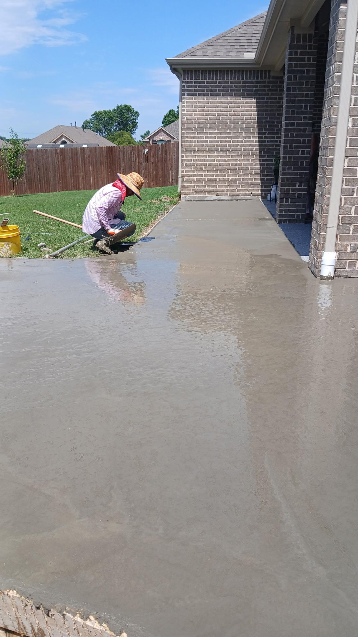 Crew hand-finishing a wet concrete slab next to a home